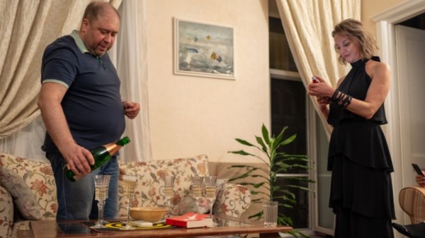 Kostiantyn pours sparkling wine for guests at his apartment