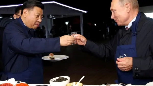 Сі та Путін у темних куртках з келихами в руках, на столі перед ними – ікра та млинці