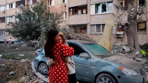 Жінка заспокоює дівчинку, яка плаче, на тлі пошкодженої машини