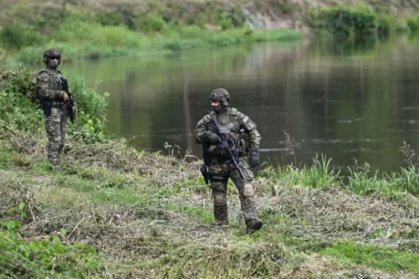 Двоє чоловіків у військовій формі зі зброєю та бронежилетами з написом