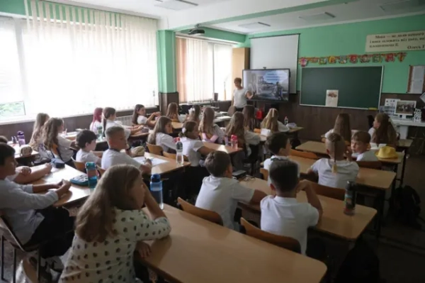 Діти сидять за партами в школі.