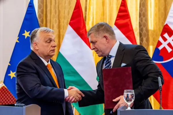 Орбан потискає руку Фіцо, який тримає бордову папку. Вони стоять за трибунами на прес-конференції на тлі прапорів Угорщини, Словаччини та ЄС.