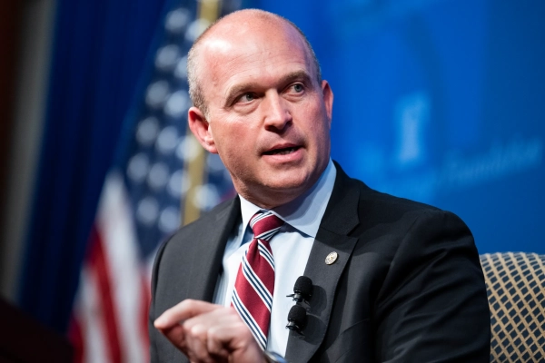 Кевин Робертс, белый мужчина, выступает на синем фоне и с флагом США.