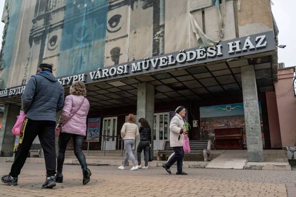 Мешканці Берегового проходять повз будинок культури; міський простір має двомовні українсько-угорські вивіски 